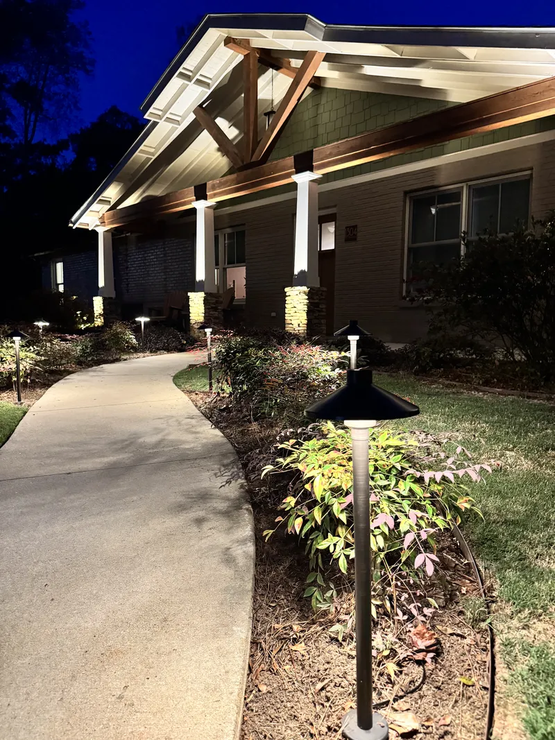 Path lights along a curved front walkway leading to a lit house entry at night