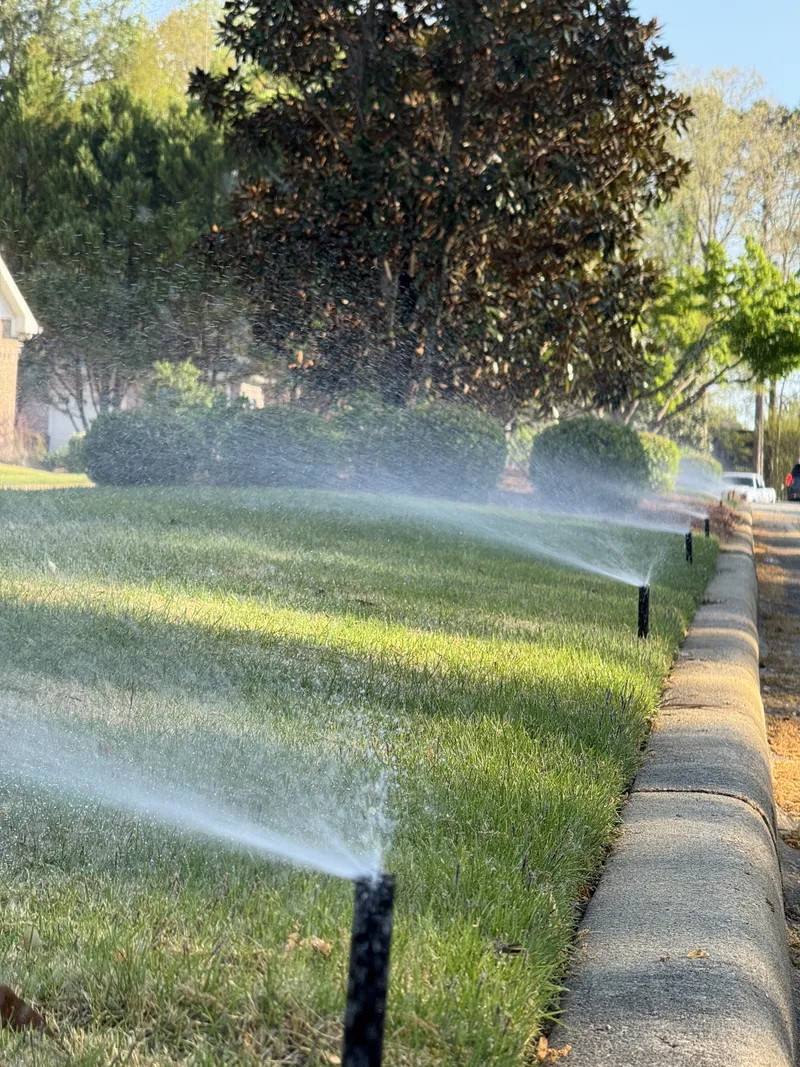 Pop-up spray heads watering a strip of lawn along a concrete curb