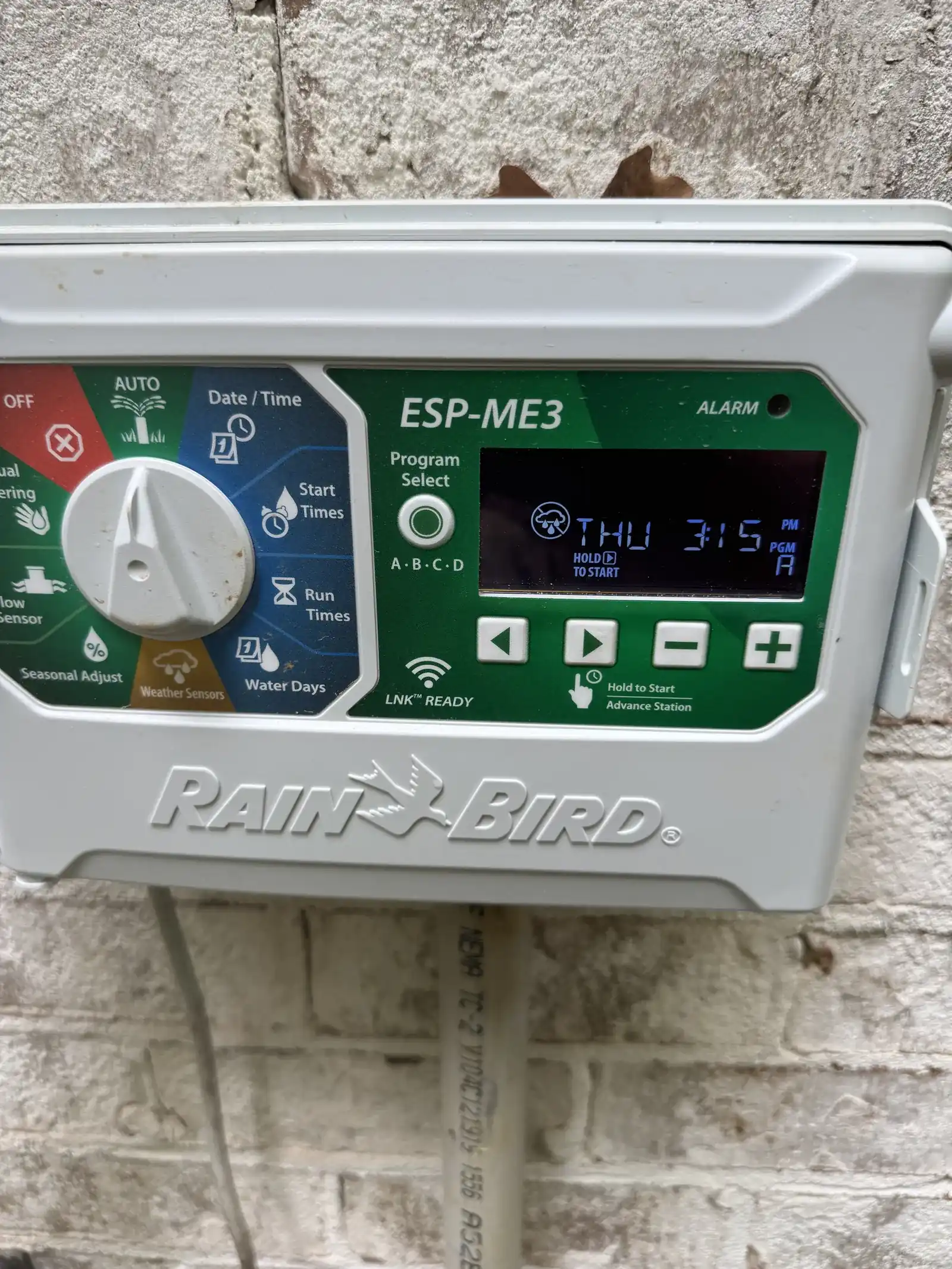 Rain Bird irrigation controller mounted on a gray exterior wall