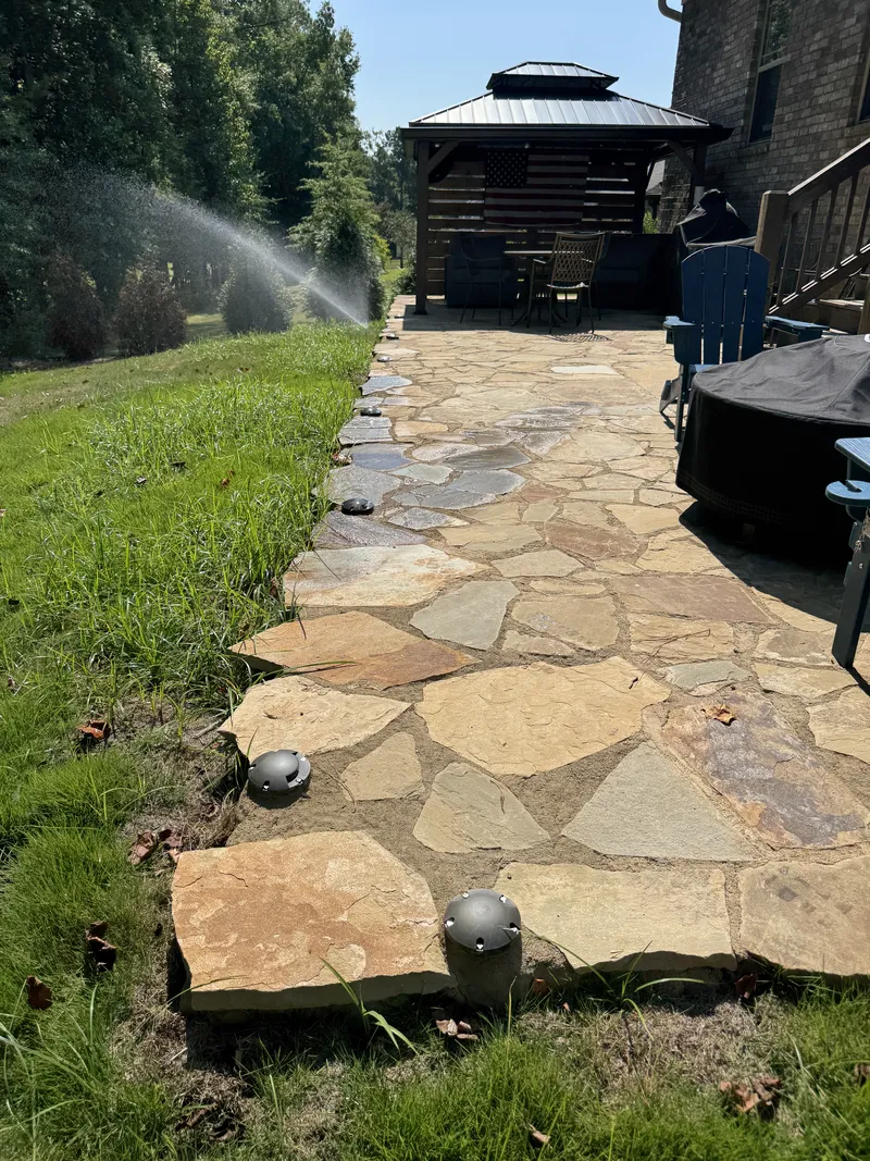 Sprinklers watering grass on both sides of a flagstone walkway